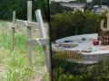 Drewniane krzyże na trawie i symbol Polski Walczącej w budowie. Park Akcji "Burza" upamiętnia bohaterów.