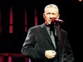 Mężczyzna w eleganckim garniturze śpiewa do mikrofonu. Może to być koncert z piosenkami Młynarskiego alfabetycznie.