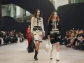 Dwie modelki prezentują kreacje od francuskich domów mody na pokazie. Jedna w ecru, druga w czerni, obie w perłach i z torebkami.