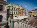 Kobieta na tle kolorowych kamienic Rynku Wielkiego w Zamościu. To miasto idealne, gdzie historia spotyka się z pięknem.