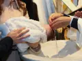 Chrzest dziecka, które może otrzymać imię Janina, symbolizujące łaskę Bożą. Woda spływa po jego głowie.