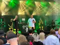Zespół na scenie podczas festiwalu czochraj bobra fest. Wokalista śpiewa, grają saksofonista, trębacz i perkusista.