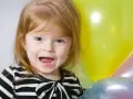 Uśmiechnięta dziewczynka, Natalia, z niebieskimi oczami i rudymi włosami, trzyma balony. Znaczenie imienia Natalia to "narodziny".