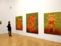 Kobieta podziwia surrealistyczne obrazy Jakuba Juliana Ziółkowskiego w galerii.