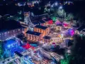 Nocny festiwal Carbon Silesia rozświetla postindustrialny krajobraz. Tłumy bawią się przy scenie, a kolorowe światła odbijają się od budynków dawnej kopalni.