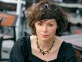 Agnieszka Glińska w czarnej sukience i naszyjniku, z okularami na głowie. Może wspominać swoich rodziców.