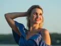 Uśmiechnięta Anita w niebieskiej sukience, z ręką we włosach. Jej imię, Anita, znaczy "łaska".