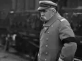 Marszałek Józef Piłsudski w mundurze, z czarną opaską na ramieniu, symbolizującą żałobę. W tle widać tłum ludzi, być może podczas uroczystości pogrzebowych, gdy Józef Piłsudski jak zmarł.
