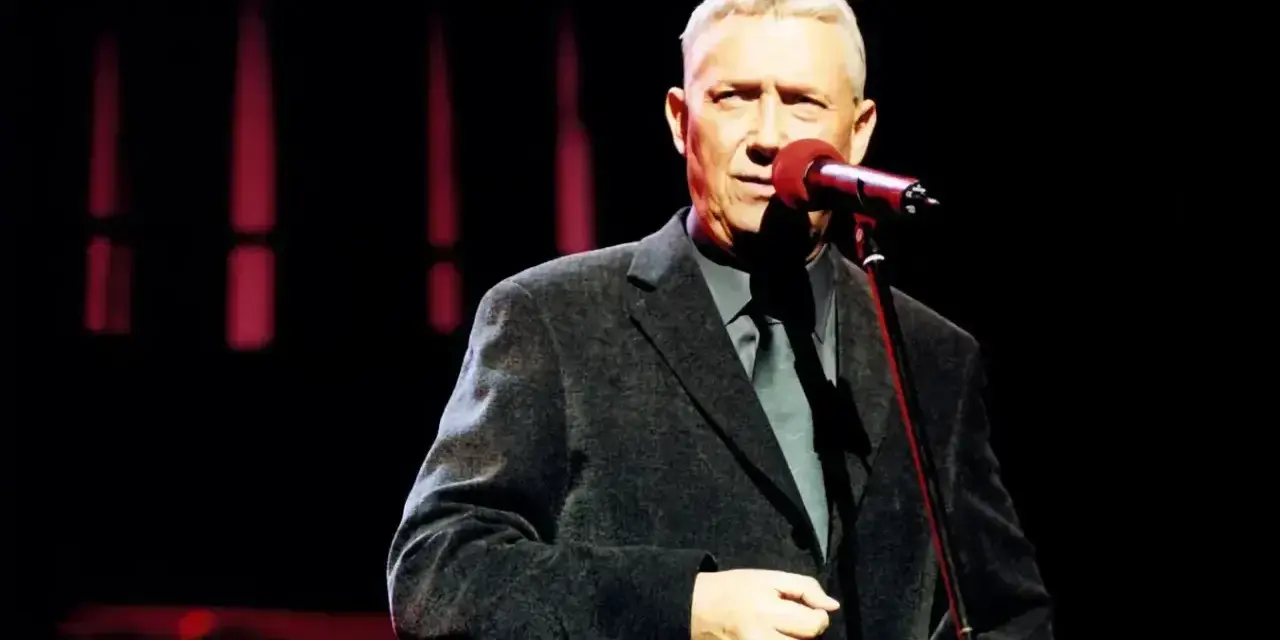 Mężczyzna w eleganckim garniturze śpiewa do mikrofonu. Może to być koncert z piosenkami Młynarskiego alfabetycznie.