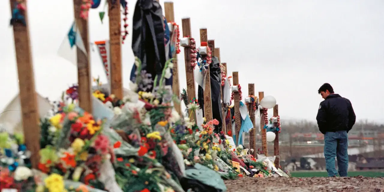 Pamięć o ofiarach masakry w Columbine High School. Krzyże ozdobione kwiatami i pamiątkami, obok stoi pogrążony w zadumie mężczyzna.