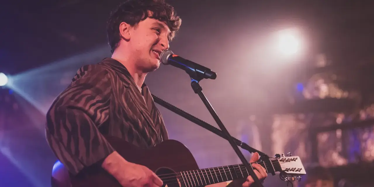 Wojtek Szumański na koncertach, śpiewający i grający na gitarze akustycznej.