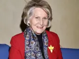 Uśmiechnięta Irena Santor w czerwonej marynarce i wzorzystym szalu, z żółtą rozetką na klapie.