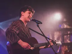 Wojtek Szumański na koncertach, śpiewający i grający na gitarze akustycznej.