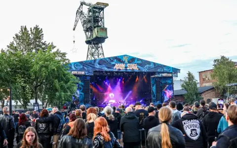 Tłum ludzi na koncercie pod wielkim dźwigiem. To jeden z wielu festiwali w Polsce, gdzie muzyka rockowa i metalowa przyciąga fanów.