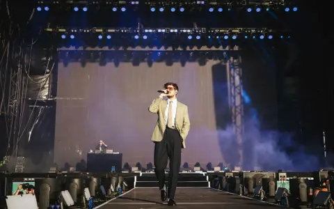 Taco Hemingway na scenie, w garniturze i z mikrofonem. Koncertowy klimat, światła i dym. To musi być koncert Taco Hemingway 2026!