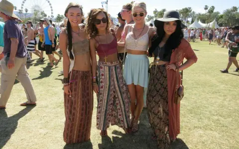 Cztery dziewczyny w letnich strojach pozują na tle festiwalu. W tle widać diabelski młyn. Ile trwa Coachella? Zwykle dwa weekendy.