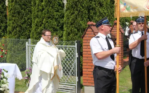 Ksiądz niesie monstrancję, a obok niego stoją policjanci. Może to być procesja, gdzie Krzysztof, jak jego imię znaczy "niosący Chrystusa", jest symbolem wiary.
