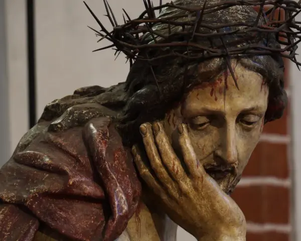 Chrystus Frasobliwy, rzeźba z koroną cierniową i krwawymi ranami, zamyślony, opiera głowę na dłoni.