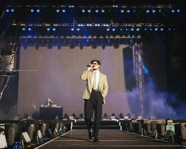 Taco Hemingway na scenie, w garniturze i z mikrofonem. Koncertowy klimat, światła i dym. To musi być koncert Taco Hemingway 2026!
