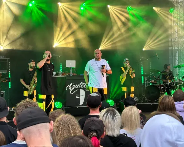 Zespół na scenie podczas festiwalu czochraj bobra fest. Wokalista śpiewa, grają saksofonista, trębacz i perkusista.