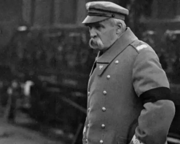Marszałek Józef Piłsudski w mundurze, z czarną opaską na ramieniu, symbolizującą żałobę. W tle widać tłum ludzi, być może podczas uroczystości pogrzebowych, gdy Józef Piłsudski jak zmarł.