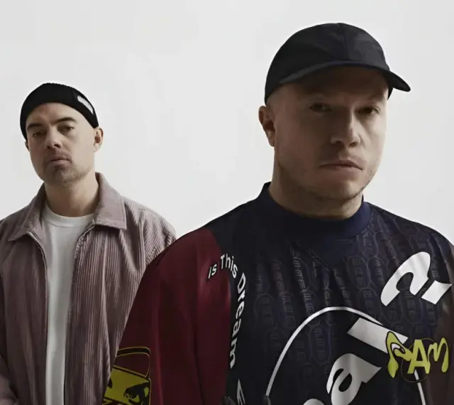Dwóch mężczyzn w czapkach, jeden w sztruksowej kurtce, drugi w bluzie z napisem "Is this dream". Czy to zapowiedź problem koncertów 2025?