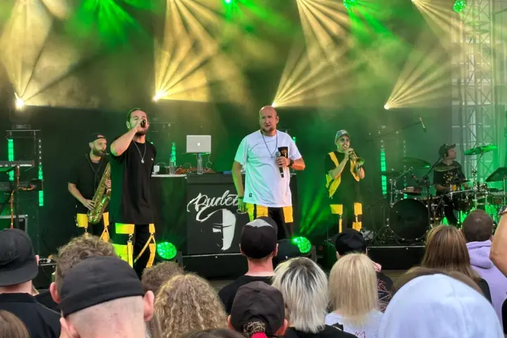 Zespół na scenie podczas festiwalu czochraj bobra fest. Wokalista śpiewa, grają saksofonista, trębacz i perkusista.