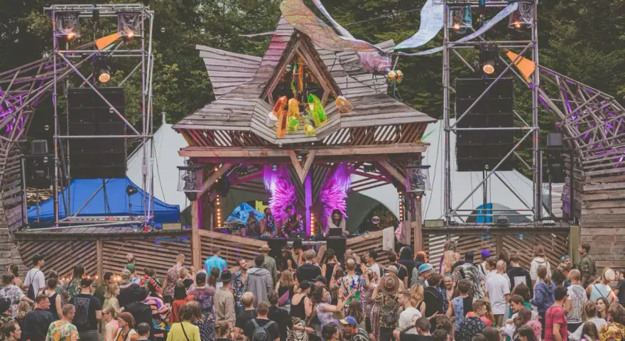 Tłum ludzi na festiwalu **summer contrast festival**. Drewniana scena z dekoracjami, głośniki i światła tworzą magiczną atmosferę.