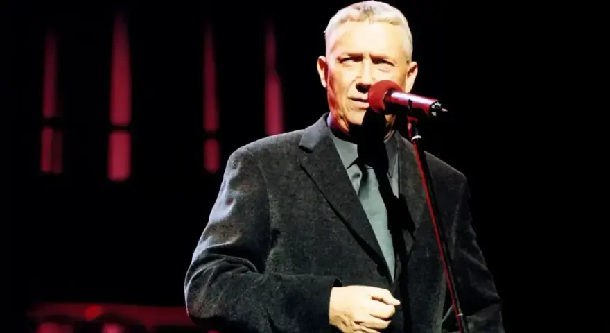 Mężczyzna w eleganckim garniturze śpiewa do mikrofonu. Może to być koncert z piosenkami Młynarskiego alfabetycznie.