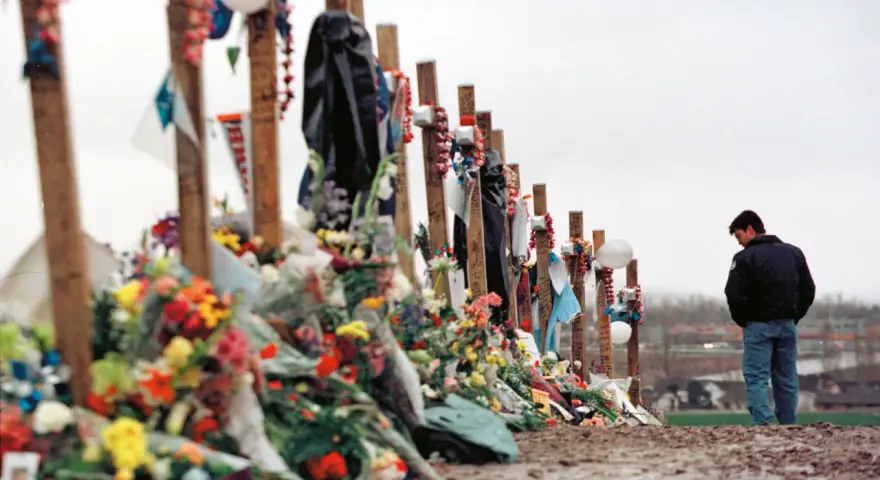 Pamięć o ofiarach masakry w Columbine High School. Krzyże ozdobione kwiatami i pamiątkami, obok stoi pogrążony w zadumie mężczyzna.
