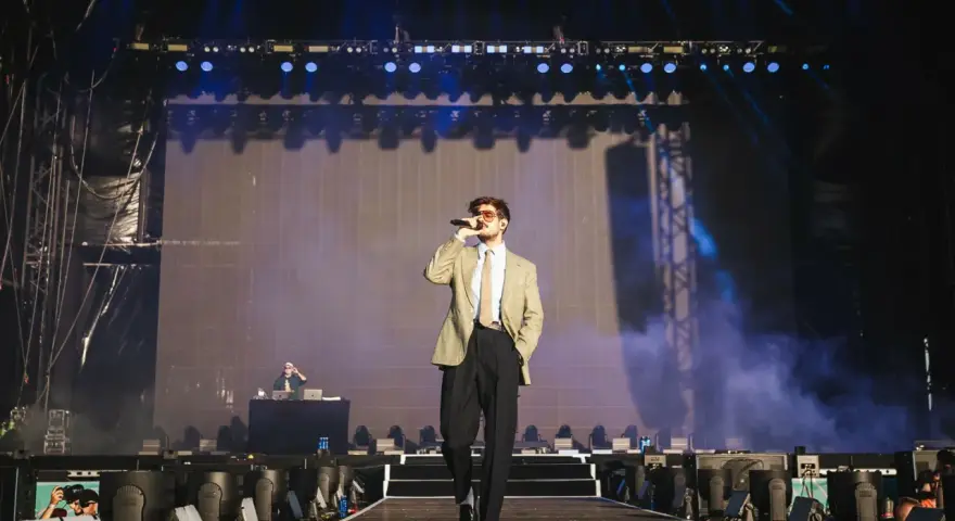Taco Hemingway na scenie, w garniturze i z mikrofonem. Koncertowy klimat, światła i dym. To musi być koncert Taco Hemingway 2026!