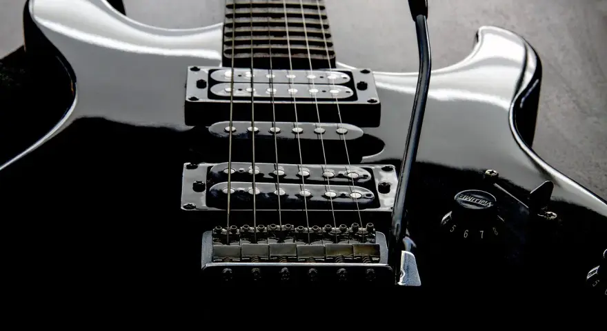 Czarna gitara elektryczna z sześcioma strunami, gotowa do rockowych riffów.