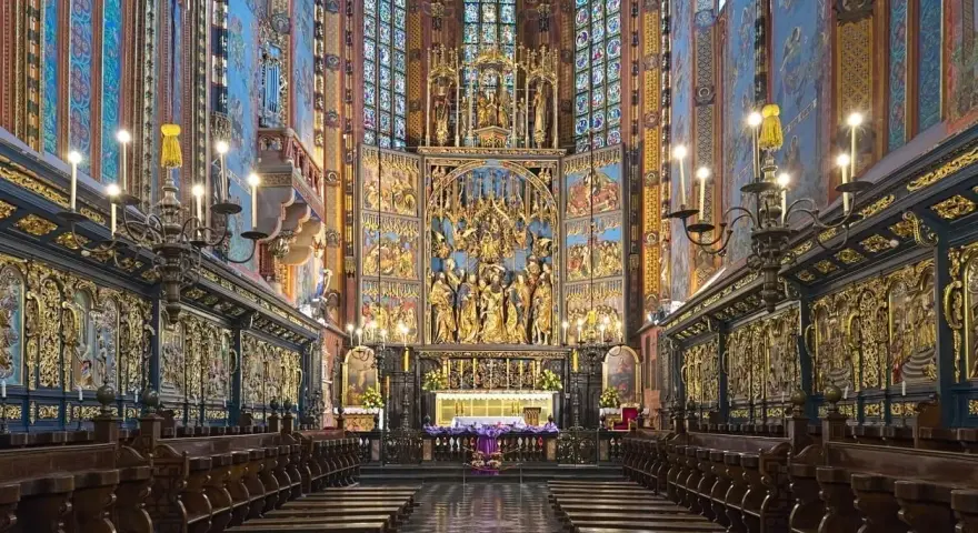Wnętrze kościoła z bogato zdobionym ołtarzem i rzędami drewnianych ławek. To jeden z najpiękniejszych kościołów w Polsce.