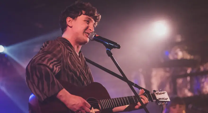 Wojtek Szumański na koncertach, śpiewający i grający na gitarze akustycznej.