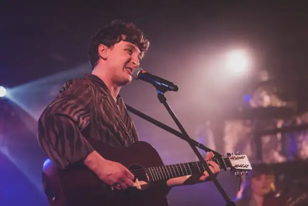 Wojtek Szumański na koncertach, śpiewający i grający na gitarze akustycznej.